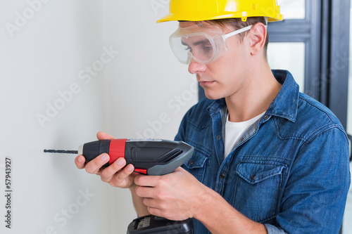 Photo: Serious young handyman using a drill Serious young handyman using a drill