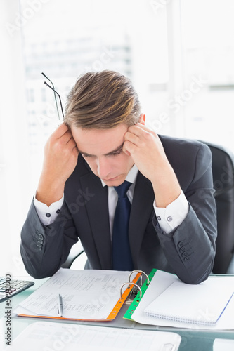 Photo: Worried businessman looking at documents in office Worried businessman looking at documents in office