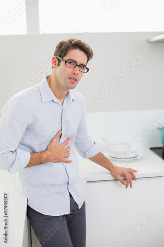 Photo: Portrait of casual man with stomach pain in kitchen Portrait of casual man with stomach pain in kitchen