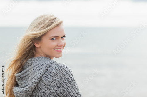 Photo: Cute young woman in gray knitted jacket on beach Cute young woman in gray knitted jacket on beach