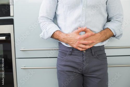Photo: Mid section of a man suffering from stomach pain Mid section of a man suffering from stomach pain