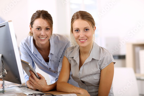 Photo: Young women in office working together on desktop Young women in office working together on desktop