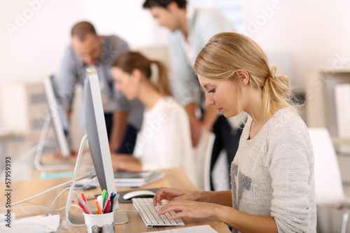 Photo: Young girl in office working on desktop computer Young girl in office working on desktop computer