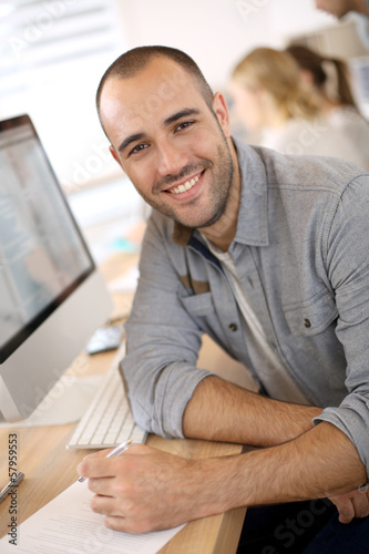 Photo: Cheerful guy sitting in front of desktop computer Cheerful guy sitting in front of desktop computer