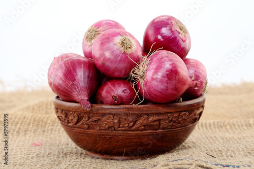 Photo: Red onions in a wooden bowl against white Red onions in a wooden bowl against white