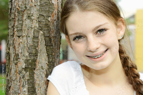 Photo: Teenager mit Zopf lehnt an Baum Teenager mit Zopf lehnt an Baum
