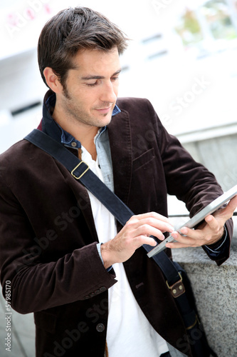 Photo: Young man connected on internet with tablet Young man connected on internet with tablet