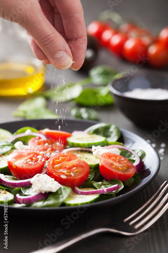 Photo: hand adding salt to vegetable salad hand adding salt to vegetable salad