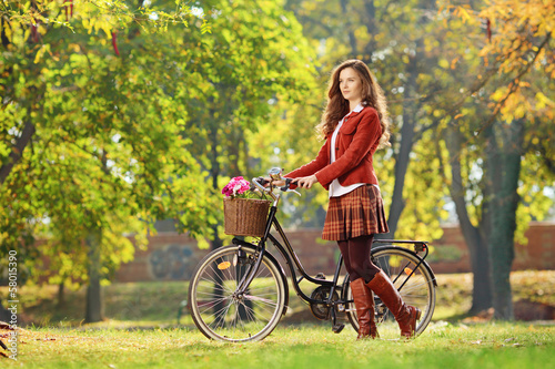 Photo: Young female walking with bicycle in park Young female walking with bicycle in park