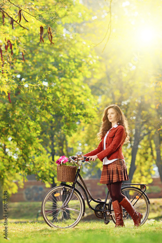Photo: Young female with bicycle relaxing in a park Young female with bicycle relaxing in a park