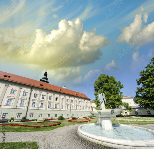 Photo: Ancient building in a beautiful city square with fountain and tr Ancient building in a beautiful city square with fountain and tr