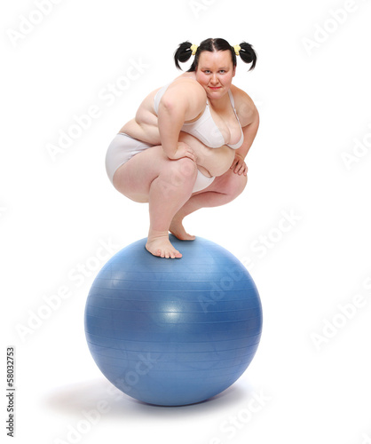 Photo: Obese woman balancing on a blue ball. Obese woman balancing on a blue ball.