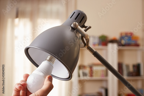 Photo: Hand changing a regular light bulb for LED Hand changing a regular light bulb for LED