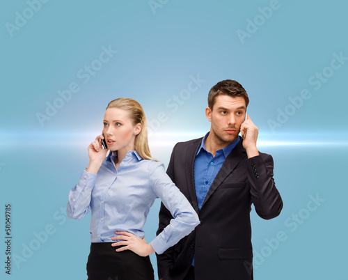 Photo: woman and man with cell phones calling woman and man with cell phones calling