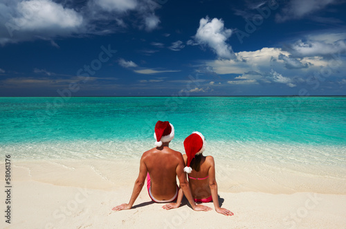 Photo: Couple in santa's hat on a beach at Maldives Couple in santa's hat on a beach at Maldives