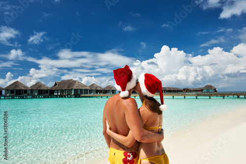 Photo: Couple in santa's hat on a beach at Maldives Couple in santa's hat on a beach at Maldives
