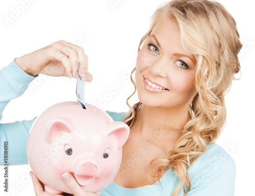 Photo: woman puts cash money into big piggy bank woman puts cash money into big piggy bank