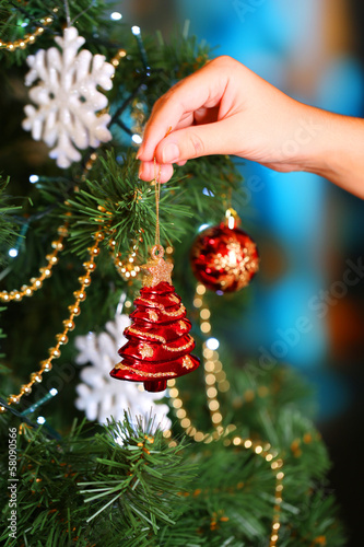 Photo: Decorating Christmas tree on bright background Decorating Christmas tree on bright background