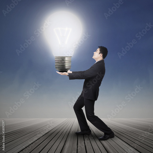 Photo: Businessman carrying light bulb Businessman carrying light bulb