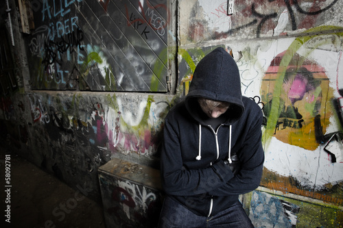 Photo: .A young against a wall with graffiti .A young against a wall with graffiti