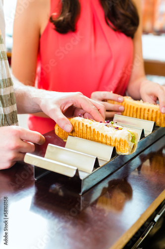 Photo: Kunden essen Hotdog in Fast Food Imbiss Kunden essen Hotdog in Fast Food Imbiss