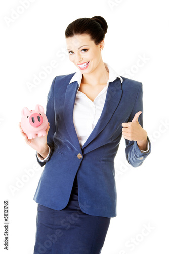 Photo: Attractive young business woman holding piggy-bank and showing O Attractive young business woman holding piggy-bank and showing O