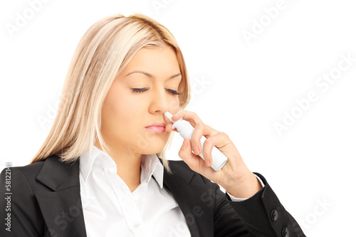 Photo: Young blond female spraying drops in her nose Young blond female spraying drops in her nose