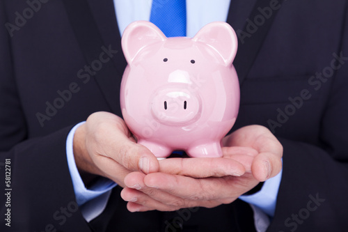 Photo: Businessman holding a piggy bank Businessman holding a piggy bank