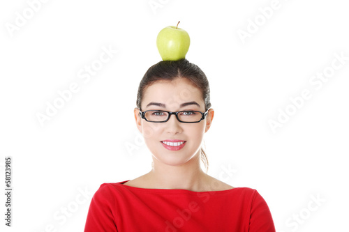 Photo: Portrait of attractive young woman with apple on head. Portrait of attractive young woman with apple on head.