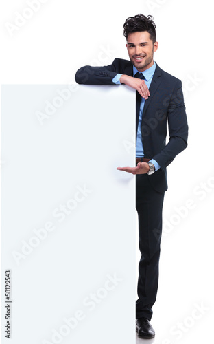 Photo: smiling young man presenting a big blank billboard smiling young man presenting a big blank billboard