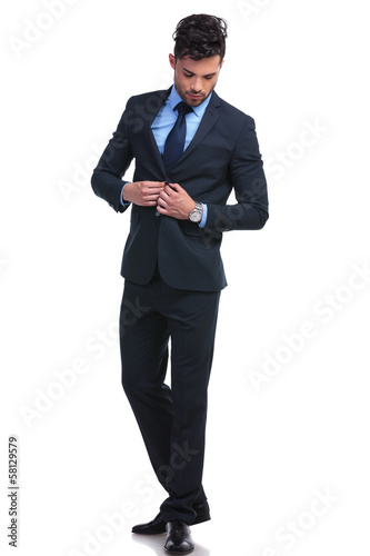 Photo: fashion business man un buttoning his suit and looking down fashion business man un buttoning his suit and looking down
