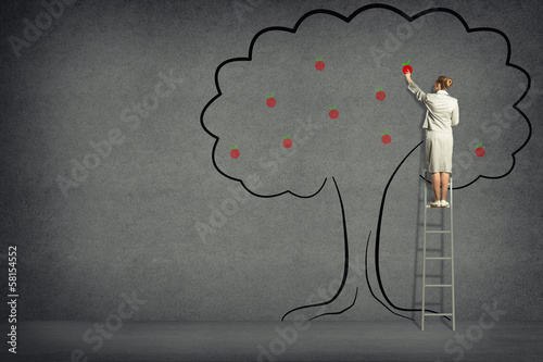 Photo: Business woman harvests from the tree Business woman harvests from the tree