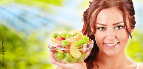 Photo: Young woman holding glass bowl with fruit salad Young woman holding glass bowl with fruit salad