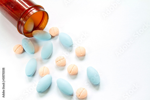 Photo: Pills spilling out of pill bottle isolated on white Pills spilling out of pill bottle isolated on white