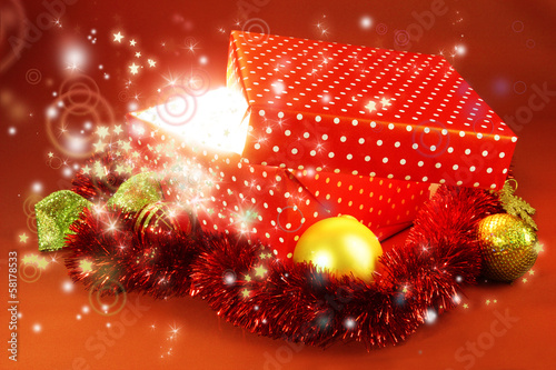 Photo: Gift box with bright light on it on red background Gift box with bright light on it on red background