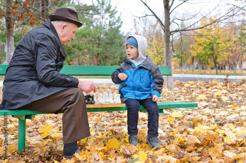Photo: Grandfather playing chess with his little boy Grandfather playing chess with his little boy