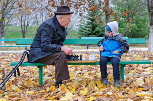 Photo: Grandfather playing chess with his little boy Grandfather playing chess with his little boy