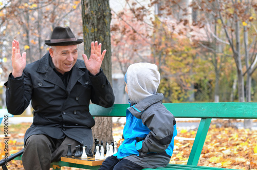 Photo: Cute little boy confronting his grandfather who is playfully Cute little boy confronting his grandfather who is playfully