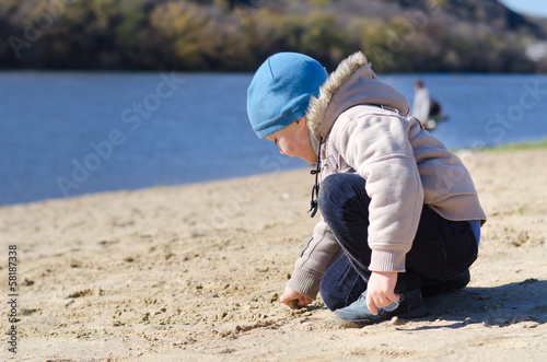 Photo: Cute little boy playing on a sandy beach Cute little boy playing on a sandy beach