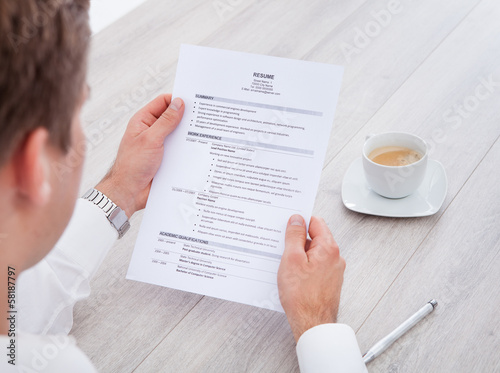 Photo: Businessman Reading Resume With Tea Cup On Desk Businessman Reading Resume With Tea Cup On Desk