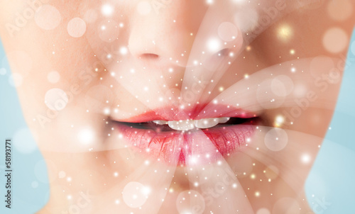 Photo: Pretty woman lips blowing abstract white lights Pretty woman lips blowing abstract white lights
