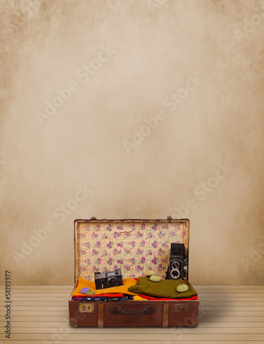 Photo: Retro tourist luggage with colorful clothes and copyspace Retro tourist luggage with colorful clothes and copyspace