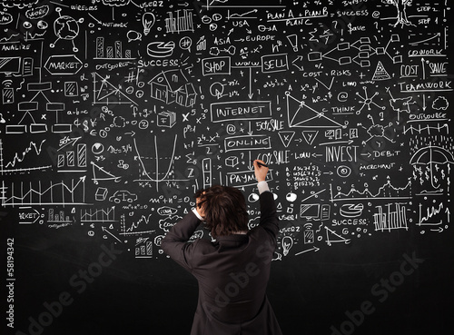 Photo: Businessman standing in front of drawn charts on a blackboard Businessman standing in front of drawn charts on a blackboard