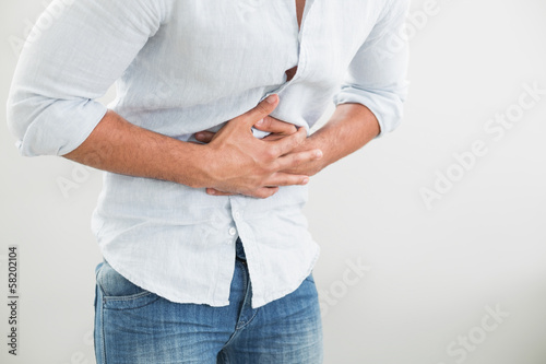 Photo: Mid section of man suffering from stomach pain Mid section of man suffering from stomach pain