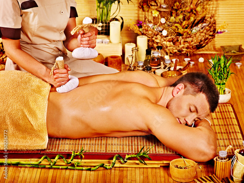 Photo: Man getting herbal ball massage treatments . Man getting herbal ball massage treatments .