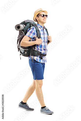 Photo: Full length portrait of a male hiker with backpack walking Full length portrait of a male hiker with backpack walking