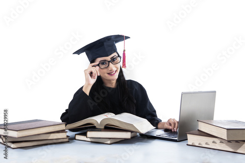 Photo: Isolated young graduate using her laptop Isolated young graduate using her laptop