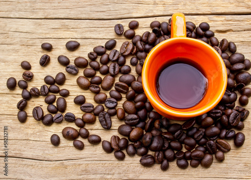 Photo: Cup of black coffee and coffee beans on wooden background. Cup of black coffee and coffee beans on wooden background.