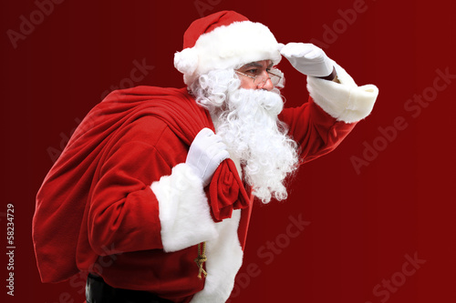 Photo: Portrait of Santa Claus carrying huge red sack with presents Portrait of Santa Claus carrying huge red sack with presents