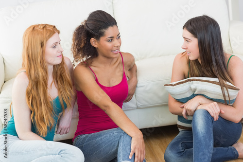 Photo: Female friends enjoying a conversation on floor at home Female friends enjoying a conversation on floor at home